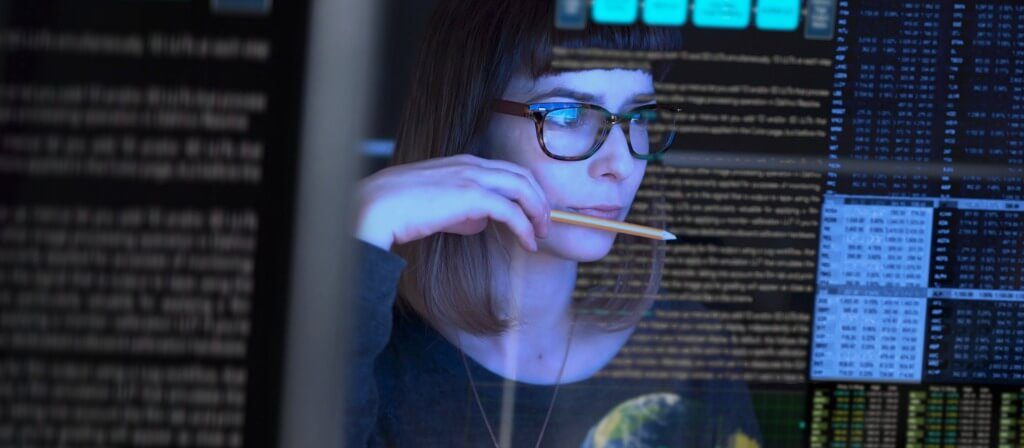 Photograph of a person through a transparent screen as they read data off of the screen.