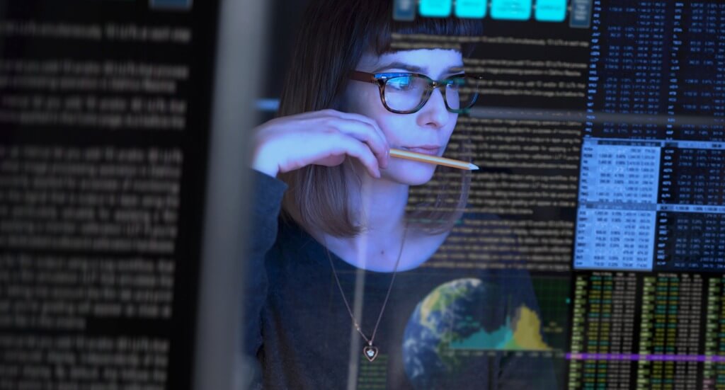 A woman with glasses looking at monitors
