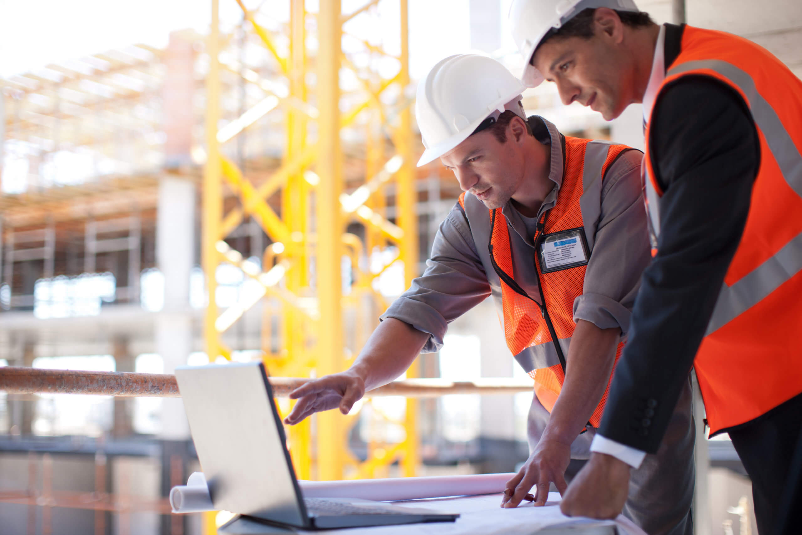 Two engineers on a construction site looking at a laptop