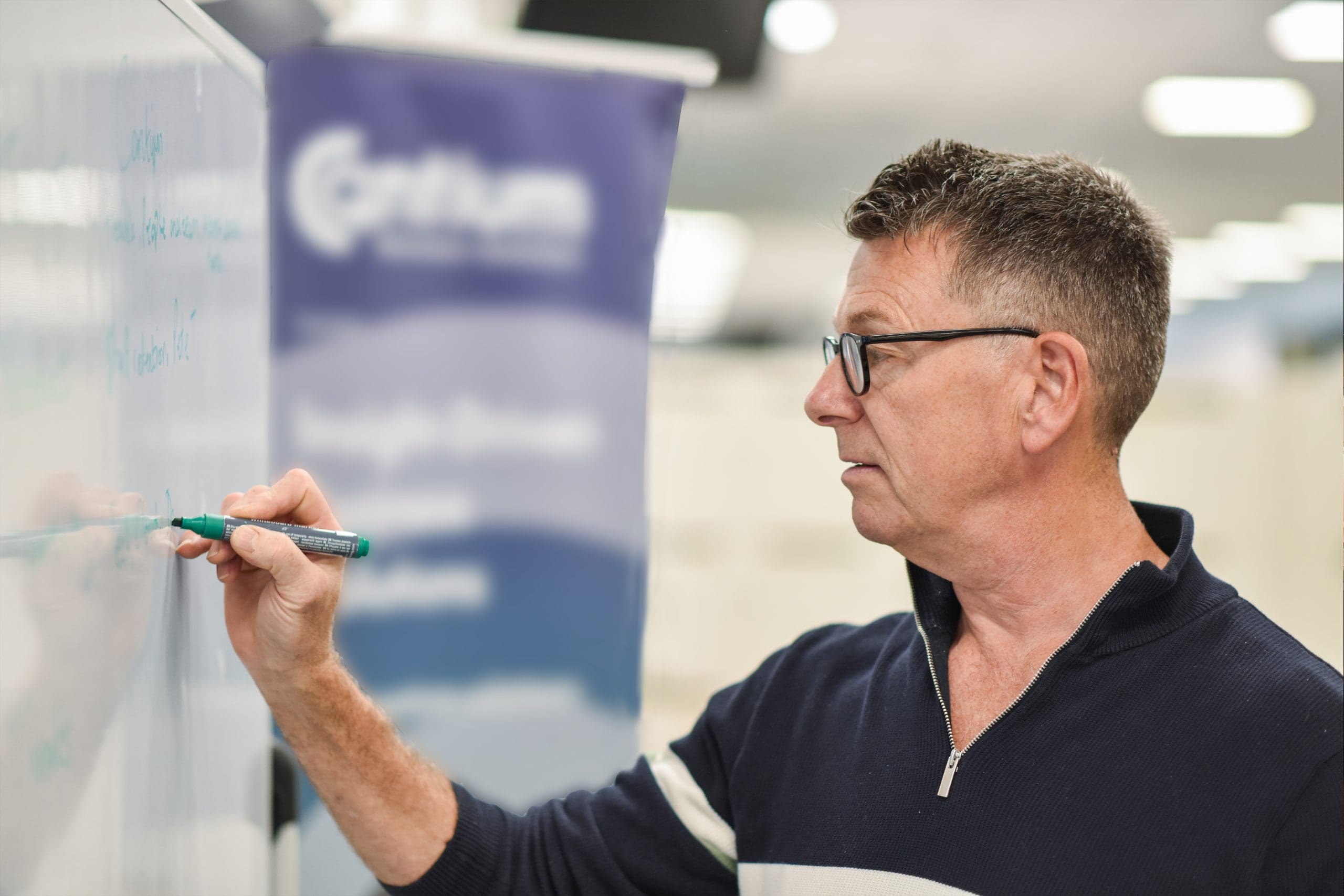 Cantium employee facing a whiteboard and writing text using a pen. Text cannot be seen.