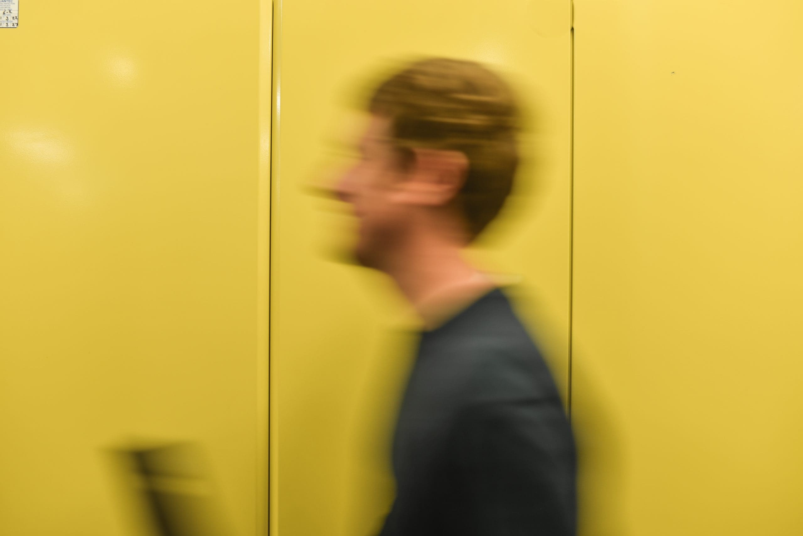 Photograph of Cantium employee walking fast past a yellow cupboard in the data centre.