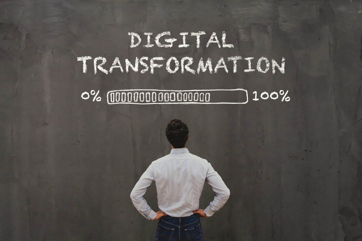 Image of a male looking up at a large chalk board with the words 'Diigital Transformation' written in chalk and a loading bar which is partically complete