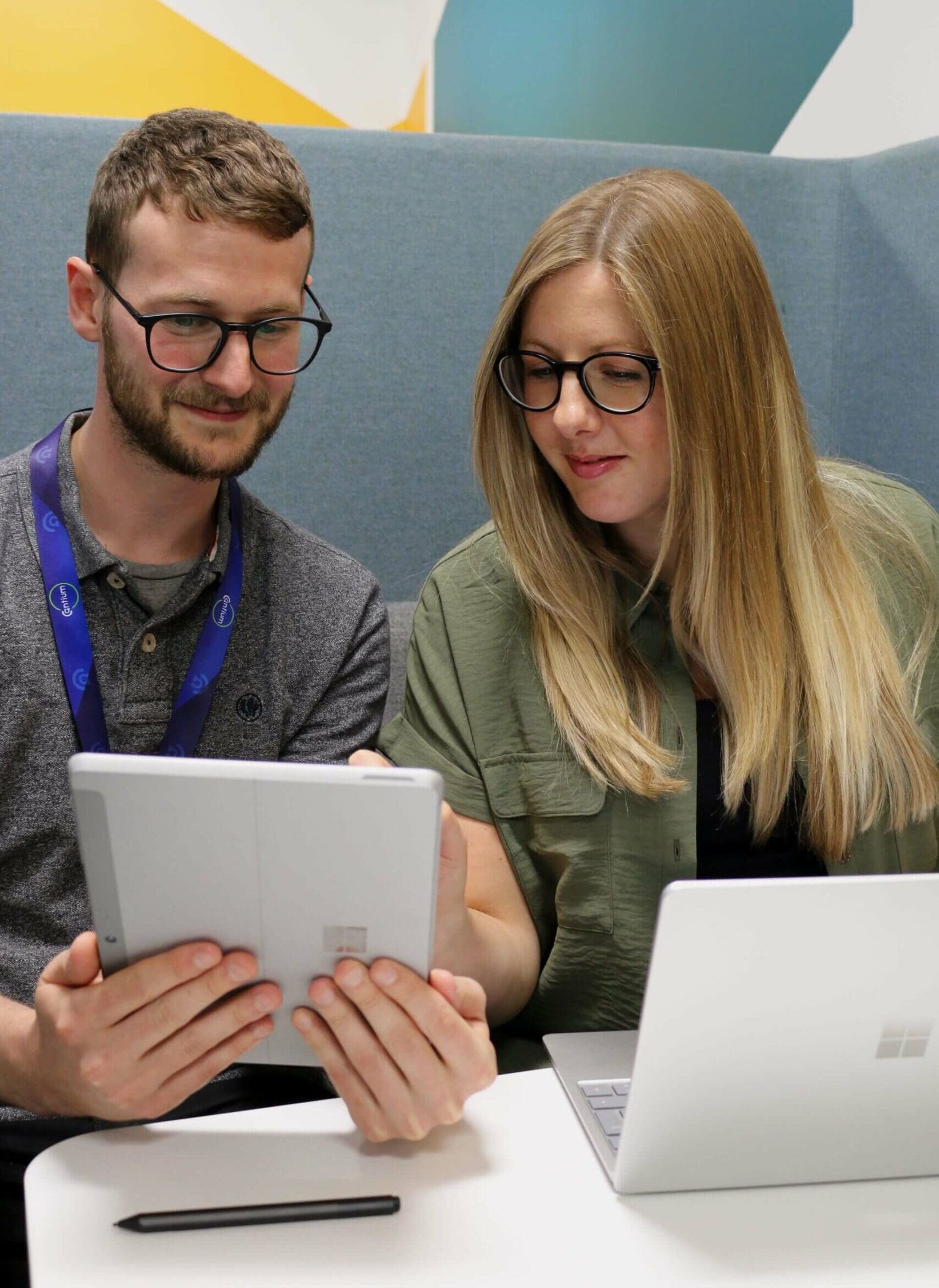 Two Cantium colleagues seated at desk with open Microsoft Surface devices in front of them.