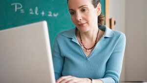 Image of woman typing on a keyboard with blackboard in the background